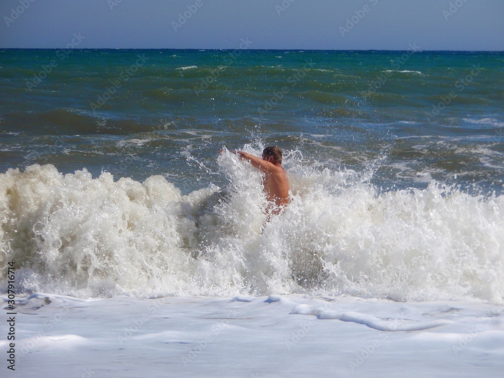 A man dives into the surging waves of a stormy sea. A man dives into the surging waves of a stormy sea.