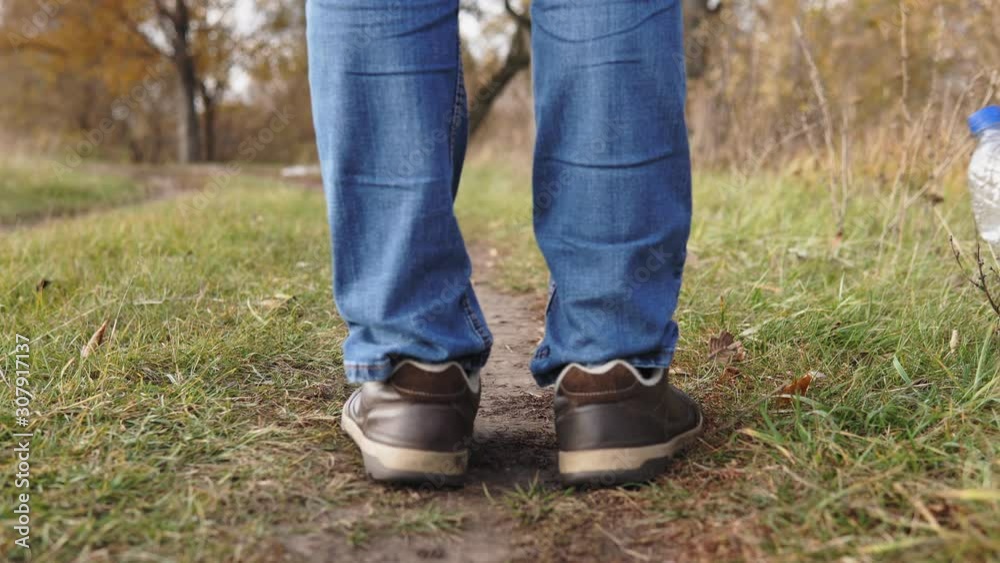 Ecological concept plastic pollution. An irresponsible man in blue jeans throws a plastic bottle onto the green grass in the park. Ecological concept plastic pollution. An irresponsible man in blue jeans throws a plastic bottle onto the green grass in the park.
