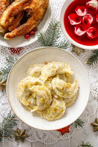 Christmas dumplings (pierogi) stuffed with forest mushrooms and cabbage on a white plate on a white holiday table, top view. Traditional Christmas eve dish in Poland