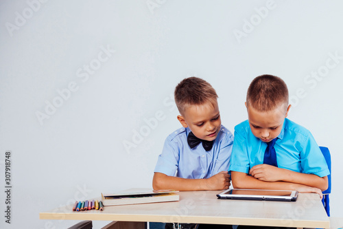 the two boys are looking at Internet Tablet school photo