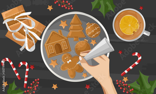 Woman hands drawing on gingerbread cookies. Gifts, berries decorations and co...