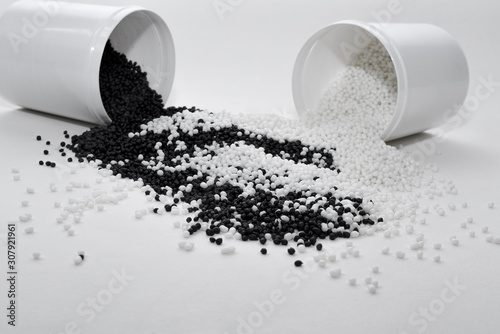 Konstfotografi Glass with black and white termoplastic elastomer granules on a white background