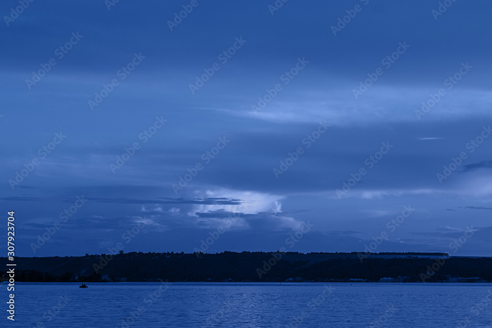 Dark blue night at seaside, dramatic clouds, space for text