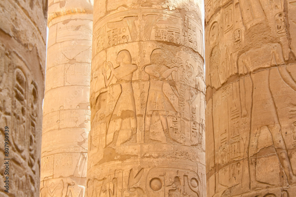 Karnak temple complex in Luxor, Egypt. Ancient bas relief with hieroglyphs on columns, pharaoh and god.