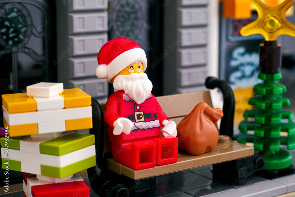 Lego Santa Claus sitting on the bench in the street with stack of gifts and  Christmas tree. Stock Photo | Adobe Stock