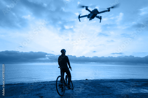 Cyclist with a drone on the coast.
