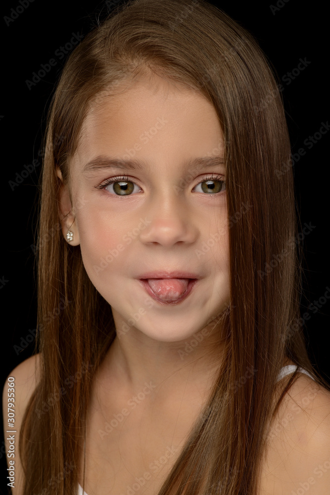 portrait of a little beautiful girl in a white T-shirt on a black background. Emotions portrait of a little beautiful girl in a white T-shirt on a black background. Emotions
