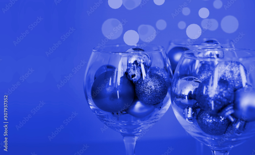 Glasses are filled with Christmas toys - concept photo of a festive New Year party, color classic Pantone 2020 blue Glasses are filled with Christmas toys - concept photo of a festive New Year party, color classic Pantone 2020 blue