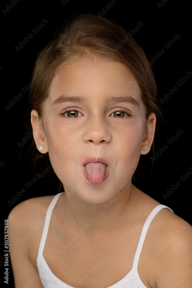 portrait of a little beautiful girl in a white T-shirt on a black background. Emotions portrait of a little beautiful girl in a white T-shirt on a black background. Emotions