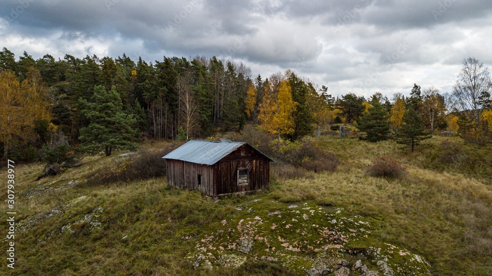 Abandoned mining house with sky clouds and autumn forest surroundings.