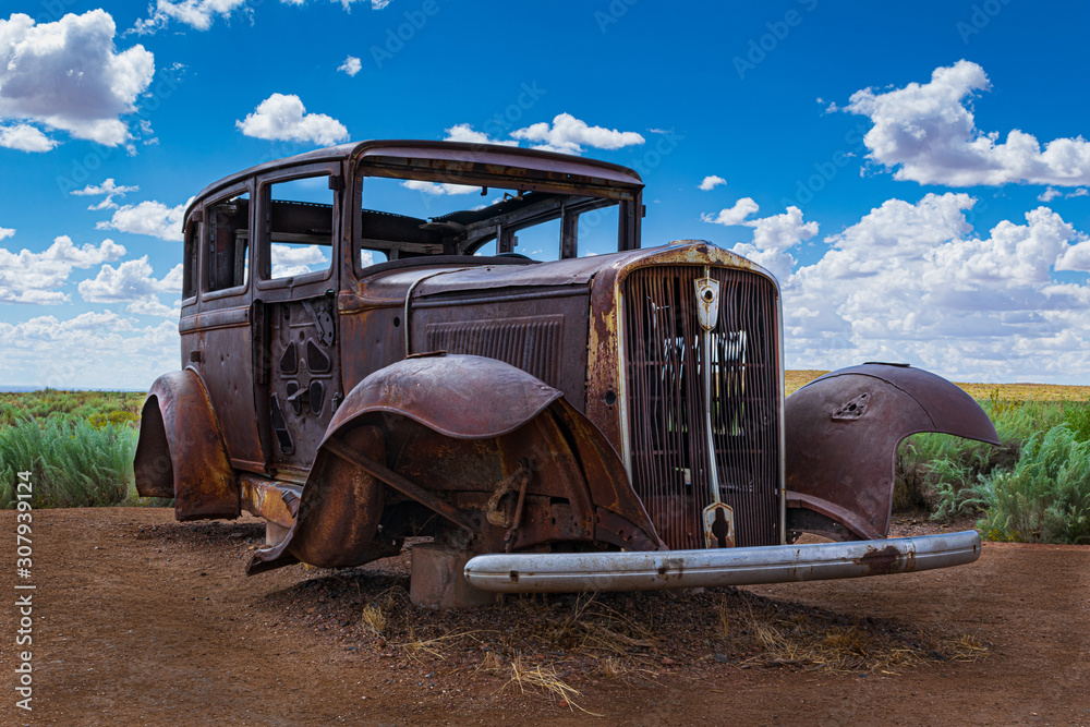 A low angle view of an old abandoned, antique, vintage automobile circa 1930 on the side of the road at the Petrified Forest National Park marks the path of old Route 66