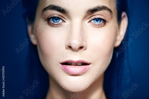 Portrait of beautiful blue-eyed woman on blue background.