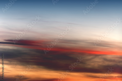 Hot sky at sunset. Orange red and dark gray long clouds on the horizon. © twinlynx