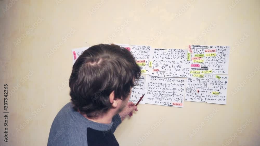 middle-aged man works with information on paper sheets that hang on the wall.scientific and research work.teacher at the workplace