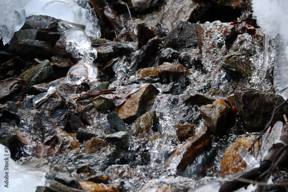 mountain stream flows trought stones, snow and ice mountain stream flows trought stones, snow and ice
