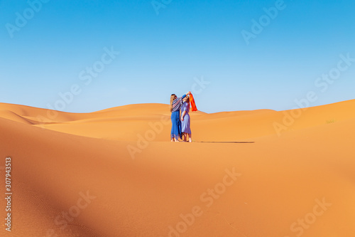 Two girls in headscarves in the Sahara desert.
