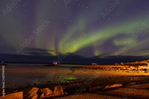 subliem moment of the northern lights, a wave of greenery in the sky with stars in the sky and a reflection in the lake