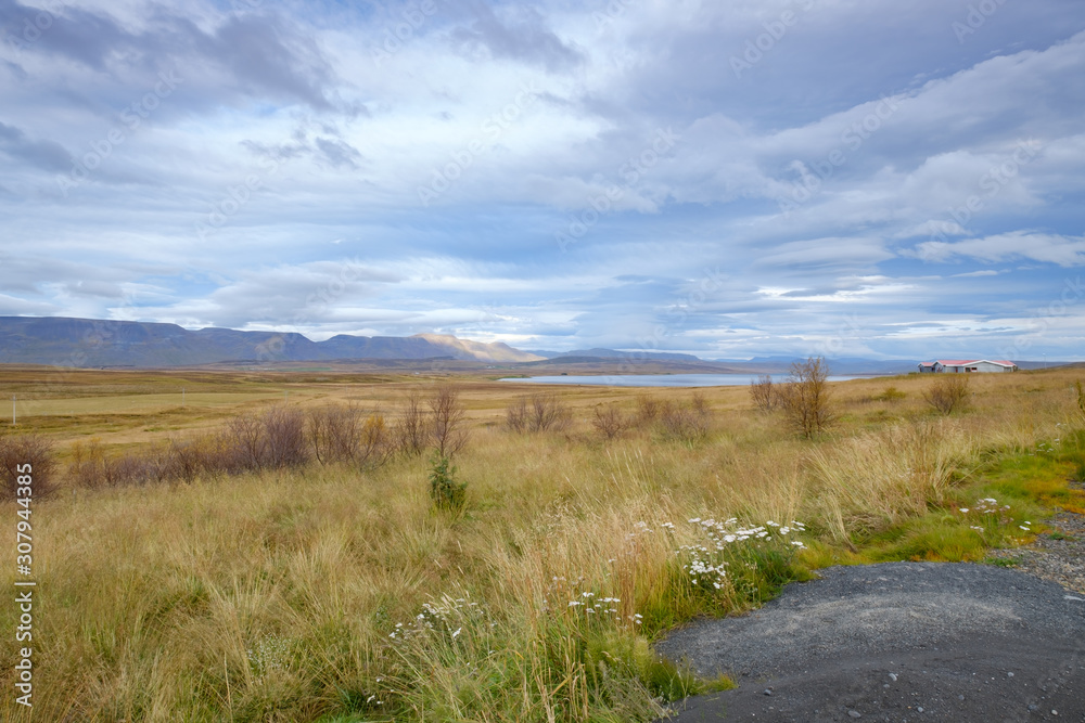 Landscape of Blondus, blue/white sky, grass, water and mountains in pretty autumn colours in Iceland