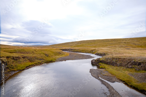 Landscape of Blondus  blue white sky  grass  water and a flowing river in the middle in pretty autumn colours in Iceland