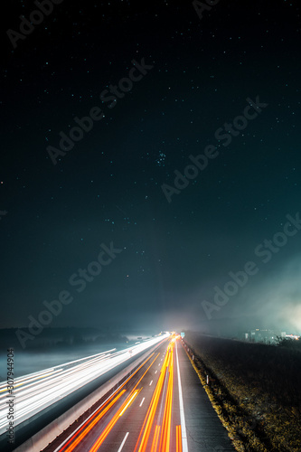 Blurry long exposure light trails of cars driving on a autobahn motorway on a night dark winter day. 