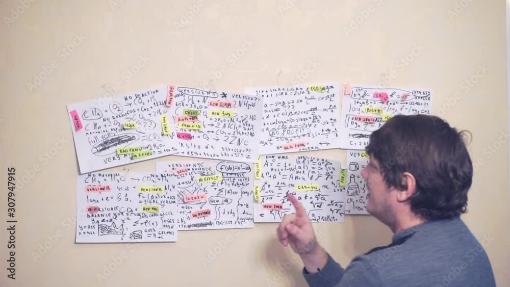 researcher works with various information on paper sheets that hang on the wall.research work. scientist in the workplace researcher works with various information on paper sheets that hang on the wall.research work. scientist in the workplace