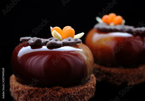 Dark brown glazed desserts with buckthorn berries and almonds on brownie base