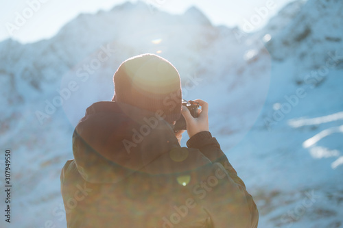 Young male photographer shooting images in the mountain in winter