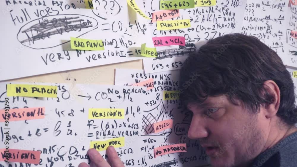 researcher works with various information on paper sheets that hang on the wall.research work. scientist in the workplace.