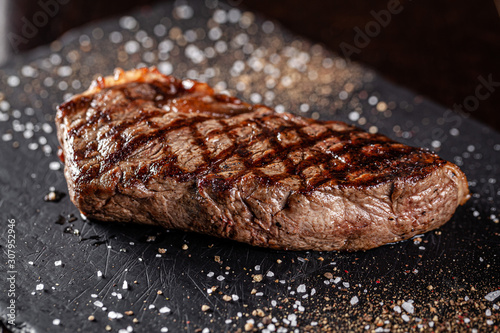 Farm organic food concept. Grilled beef steak with grill. Fried steak on on black slate, on a black background.
