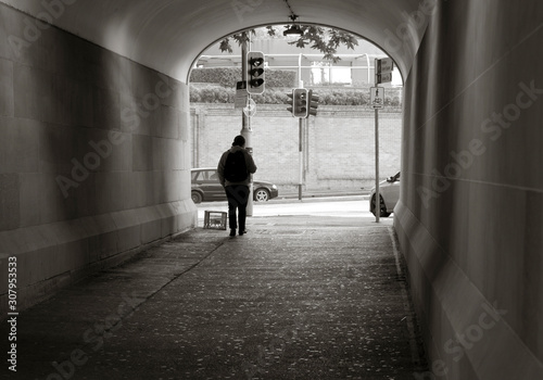 Man walking towards the exit of a pedestrian tunnel