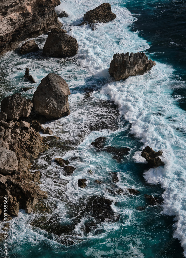 Aerial view to ocean waves with rocks. Blue water background. Bali, Indonesia. Aerial view to ocean waves with rocks. Blue water background. Bali, Indonesia.