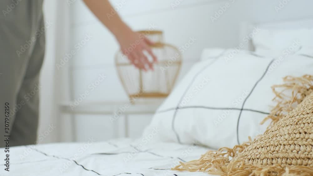 boho style bedroom. focus on the pillows on the bed. in the background a woman arranges home furnishings