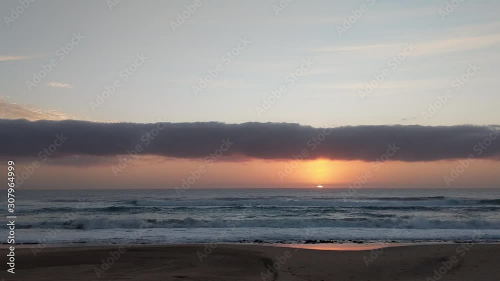 Slow sunrise as waves gently crash on a warm tropical beach Slow sunrise as waves gently crash on a warm tropical beach