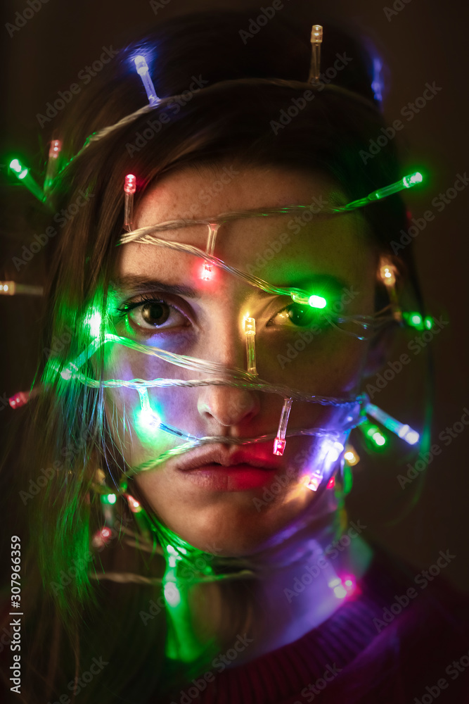 Portrait of a girl with the lights on her face. New Year portrait. Unhappy girl. Holiday. Portrait of a girl with the lights on her face. New Year portrait. Unhappy girl. Holiday.