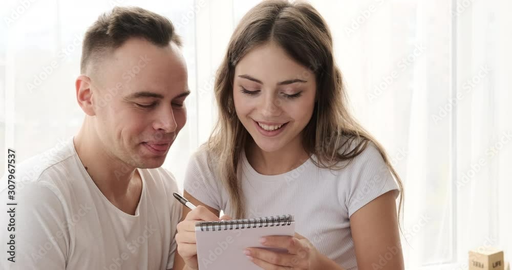 Young couple having fun writing shopping list in notepad Young couple having fun writing shopping list in notepad