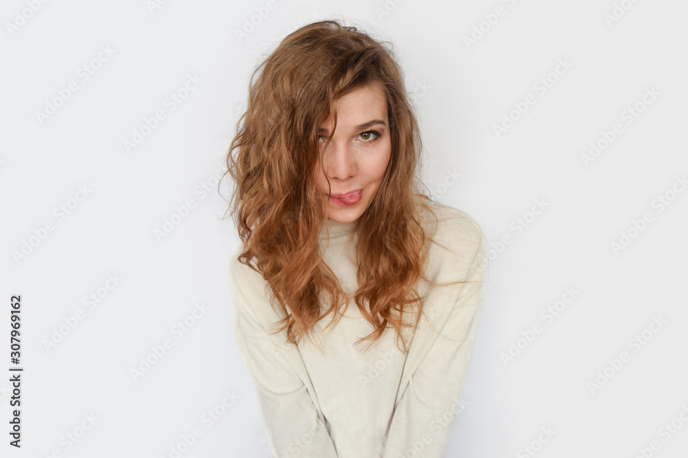 Playful girl shows tongue and smiles on white background. Playful girl shows tongue and smiles on white background.
