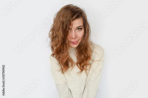 Playful girl shows tongue and smiles on white background.