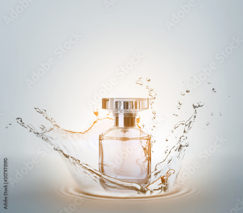 Bottle of perfume with splash on light background photo