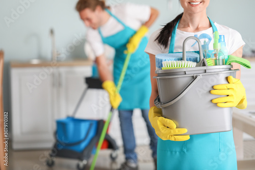 Female janitor with cleaning supplies in kitchen