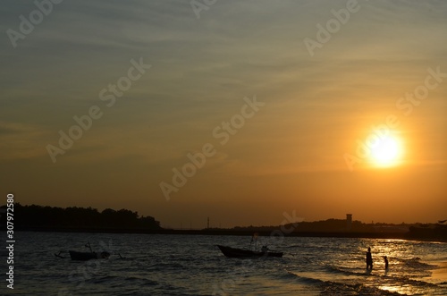 people silhouette play on the beach with the sunset as background and fisherman boat silhouette. in Borneo,Indonesia.