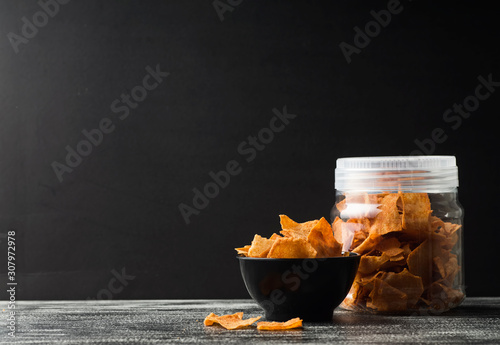 Crispy popiah fried with cheese and curry powder over black wooden background and plastic container photo