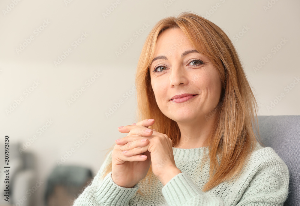 Beautiful mature woman sitting in armchair at home Beautiful mature woman sitting in armchair at home