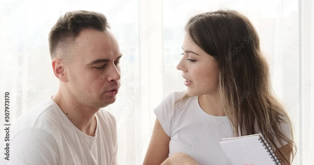 Young couple planning and writing shopping list in notepad at home Young couple planning and writing shopping list in notepad at home