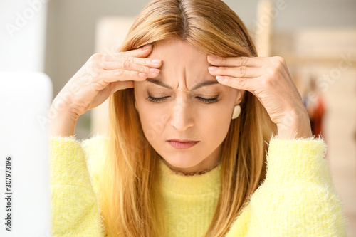 Mature woman suffering from head ache in office