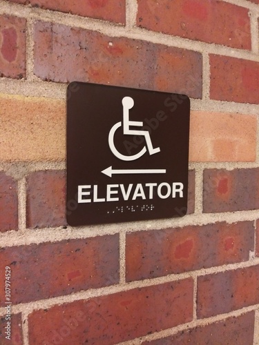 A handicap elevator sign on a brick wall