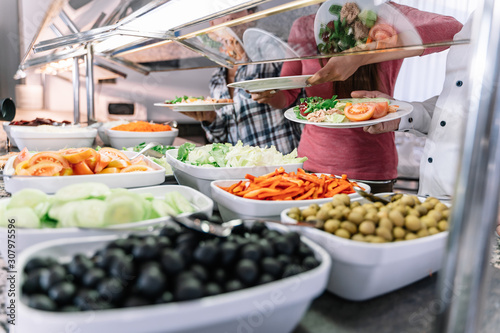 Obraz na plátně Plates with chopped pepper, tomatoes, olives and salad at a self-service restaur