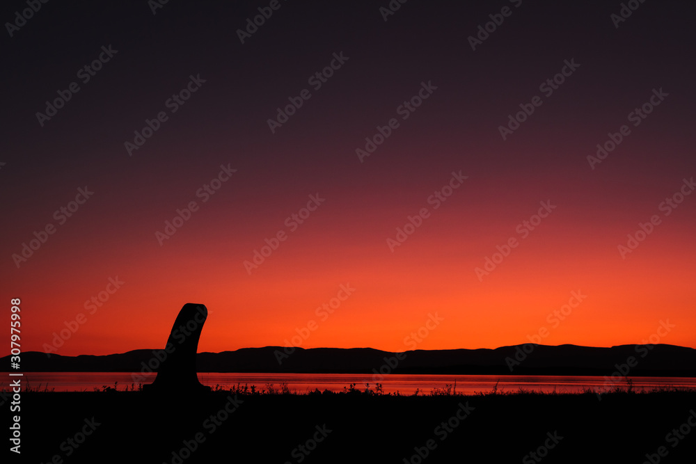 silhouette of a concrete pole at sunset with river and mountaims