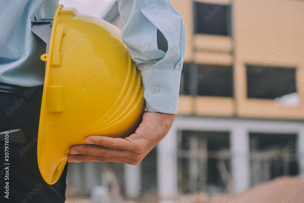 Foreman construction project control holding hard hat safety at estate building