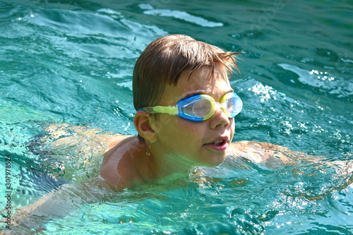 Boy child in water glasses in the pool. Children swimming in a private pool. Sports holidays.