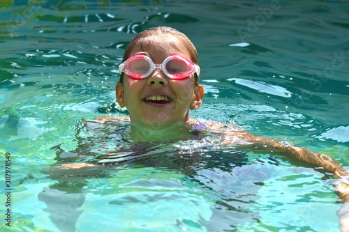 Portrait of a girl in swimming goggles. Happy girl swims in the pool.